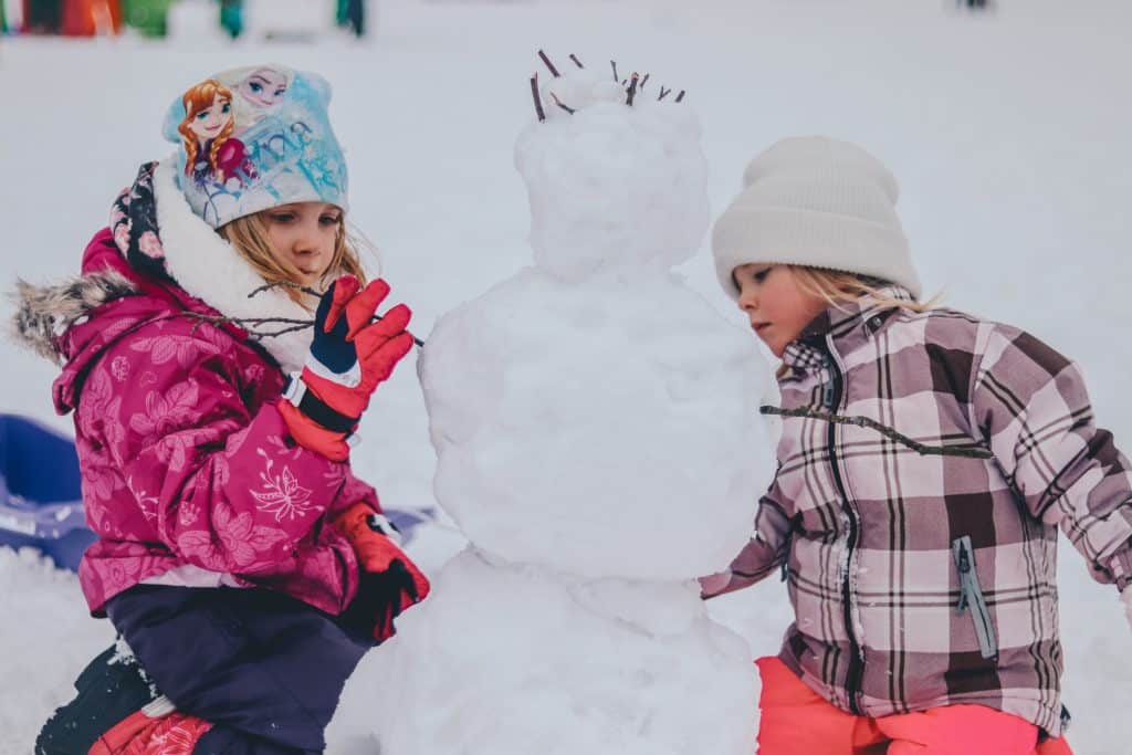 deux enfants qui construisent un bonhomme de neige