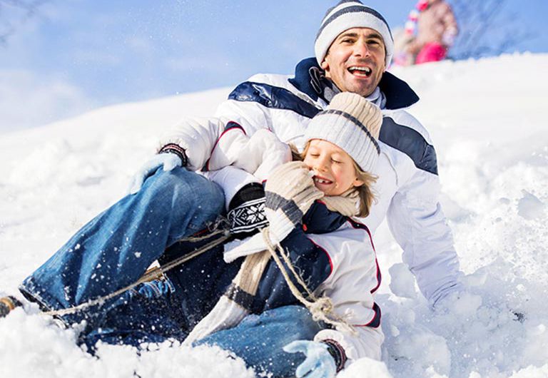 père et fils faisant de la luge dans la neige